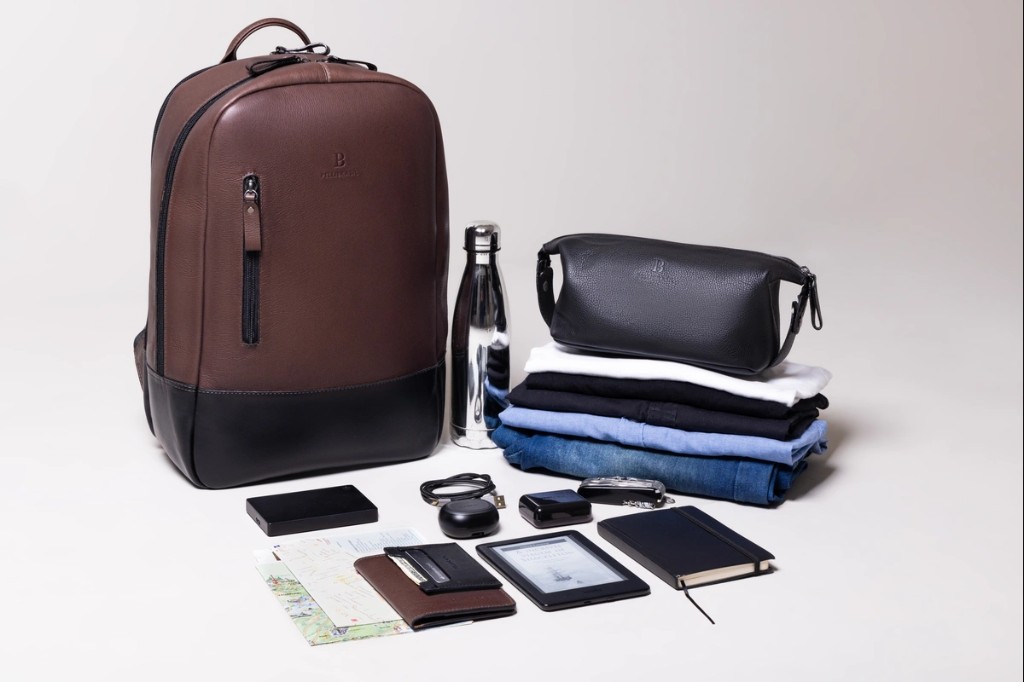 mochila de couro marrom e itens que comporta nela 