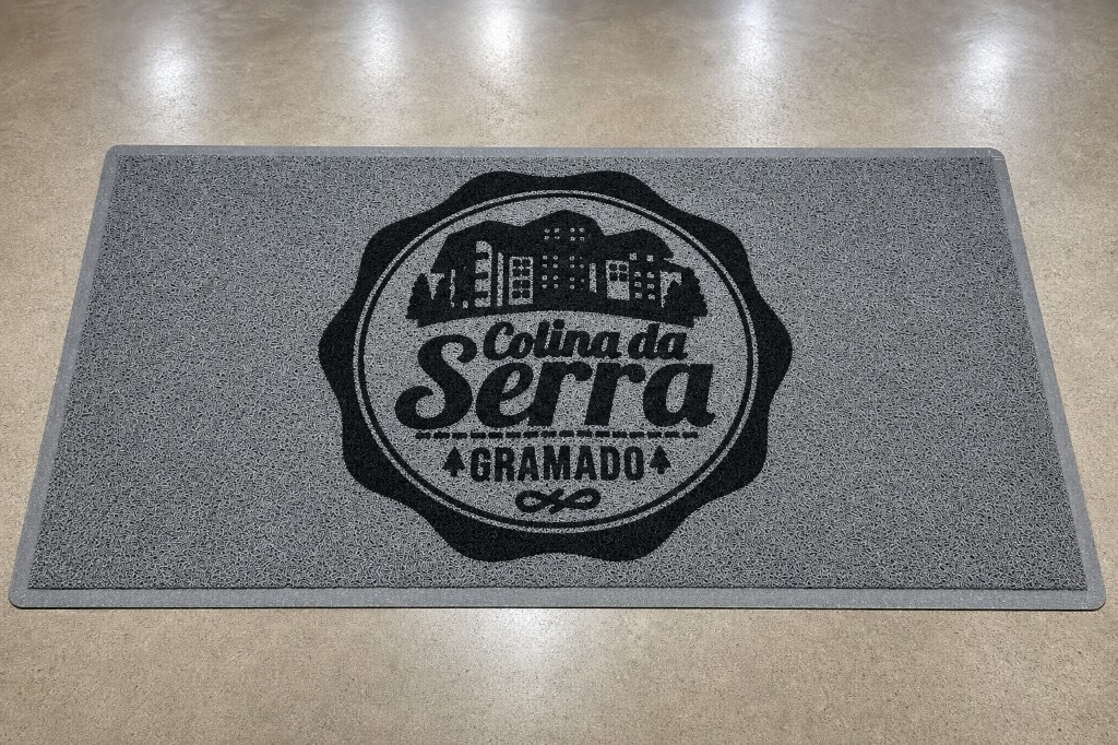 Capacho personalizado da Colina da Serra em cinza com o nome e a localização GRAMADO em destaque, instalado na entrada sobre piso premium, ideal para hotéis, pousadas e estabelecimentos de hospitalidade.