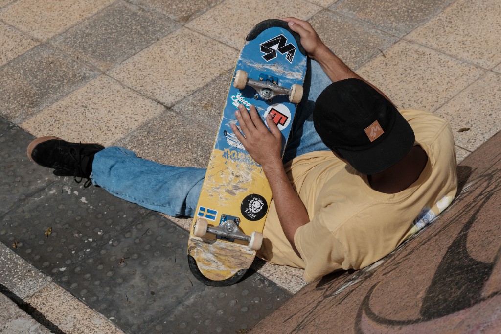 Skatista iniciante descansando após um rolê de skate na rua, mostrando o skate como lifestyle e processo de evolução.