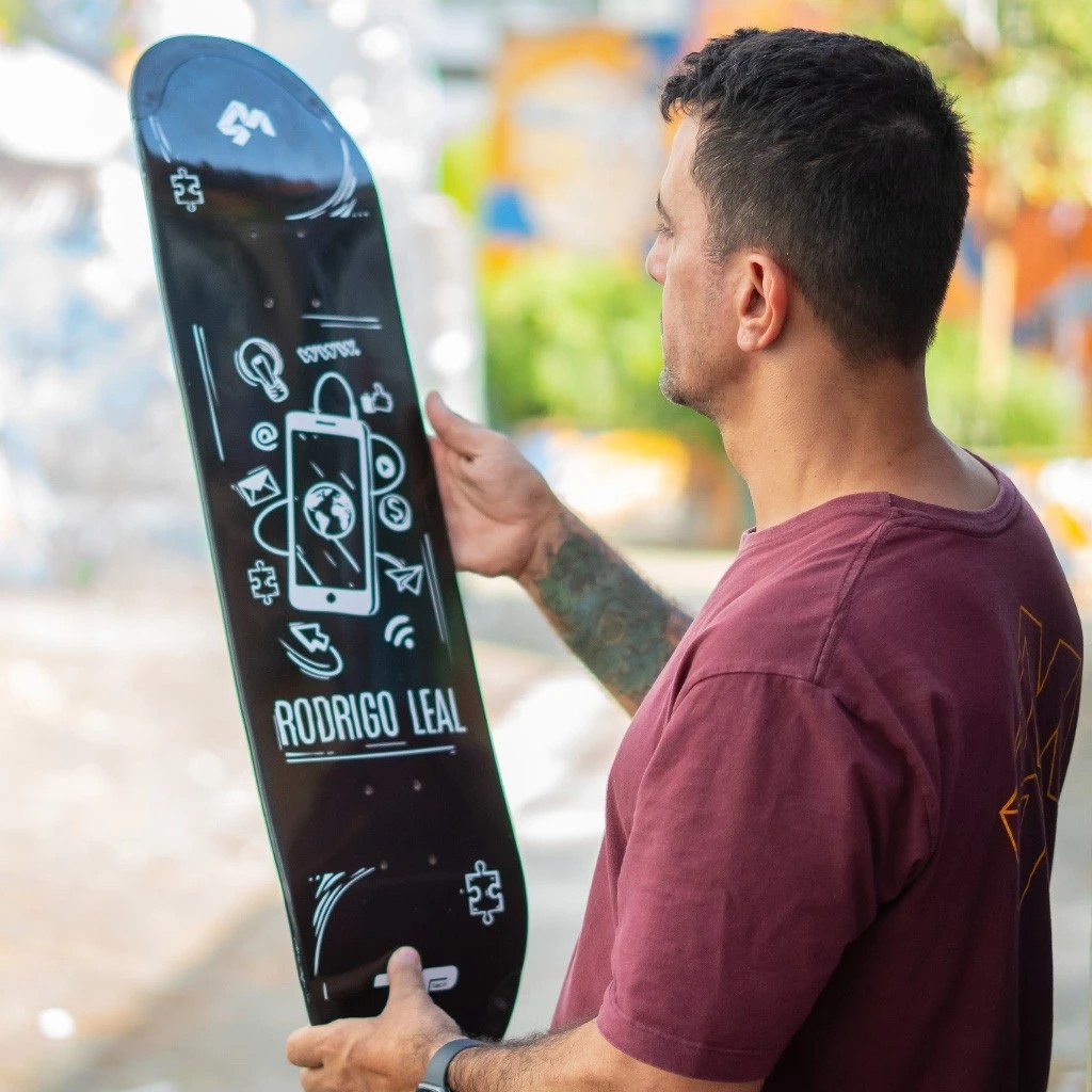 Skatista segurando um shape de skate preto da 4Msb, modelo Rodrigo Leal, destacando a tecnologia TIPtech integrada no nose e no tail.