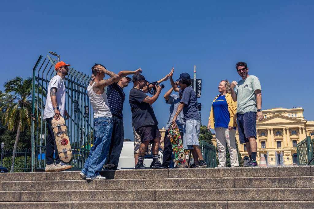 Fotografia ao ar livre de uma equipe de skatistas de rua (crew) comemorando e batendo as mãos em uma escadaria de um pico clássico, enquanto um videomaker registra a sessão em um dia ensolarado. Filmar manobras na rua exige repetição extrema, e o impacto constante em escadas e gaps destrói rapidamente a madeira convencional, causando o desgaste do razor tail ou a quebra no meio da prancha. Para suportar o ritmo intenso das ruas, a evolução do shape se faz necessária. Na imagem, os skatistas seguram pranchas equipadas com a tecnologia TIPtech da 4Msb by Skateovation. Essa engenharia de skate absorve os choques nas extremidades, garantindo um pop duradouro e provando ser um shape que não quebra facilmente, o que aumenta a vida útil do equipamento em até 3x. O reforço estrutural não altera o peso do skate e preserva o estalo nítido e seco. Ao escolher o melhor shape para manobras, a equipe eleva o nível da sessão e fortalece o consumo consciente no skate, unindo alta performance ao skate sustentável.