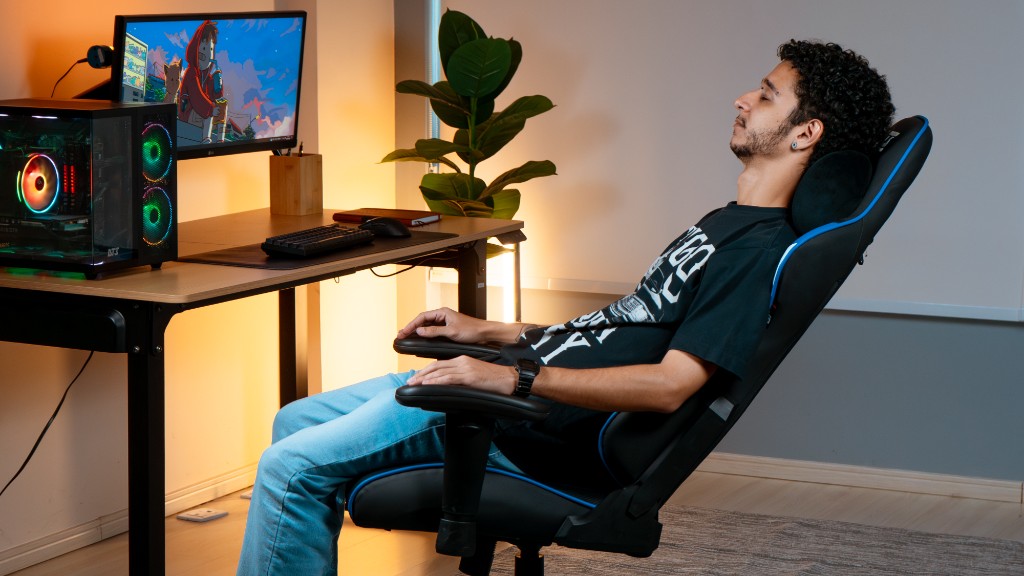 Usu&aacute;rio utilizando cadeira gamer ergon&ocirc;mica DT3 com encosto reclinado, demonstrando conforto, apoio lombar e postura correta no setup.