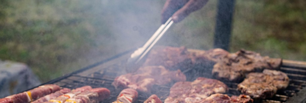 parrillero usando accesorios Grill West mientras cocina asado de Navidad