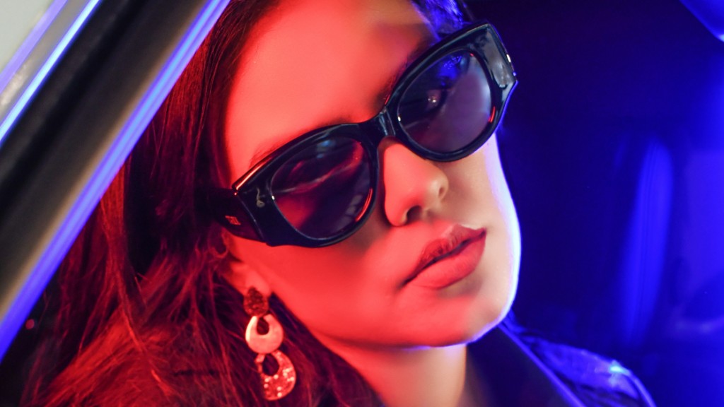 Close-up dram&aacute;tico de mulher com &oacute;culos de sol geom&eacute;trico TRIIIX, luz e sombra em ambiente urbano sofisticado.