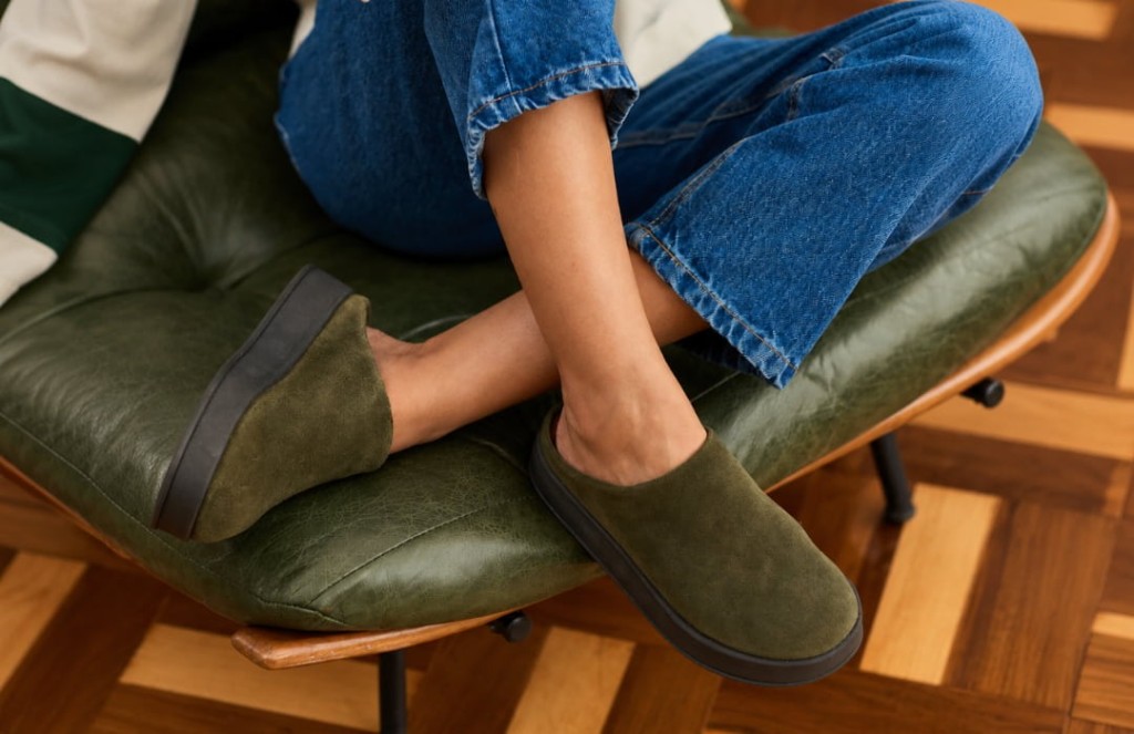 Mulher usando clog feminino verde em camur&ccedil;a com cal&ccedil;a jeans em um ambiente interno.