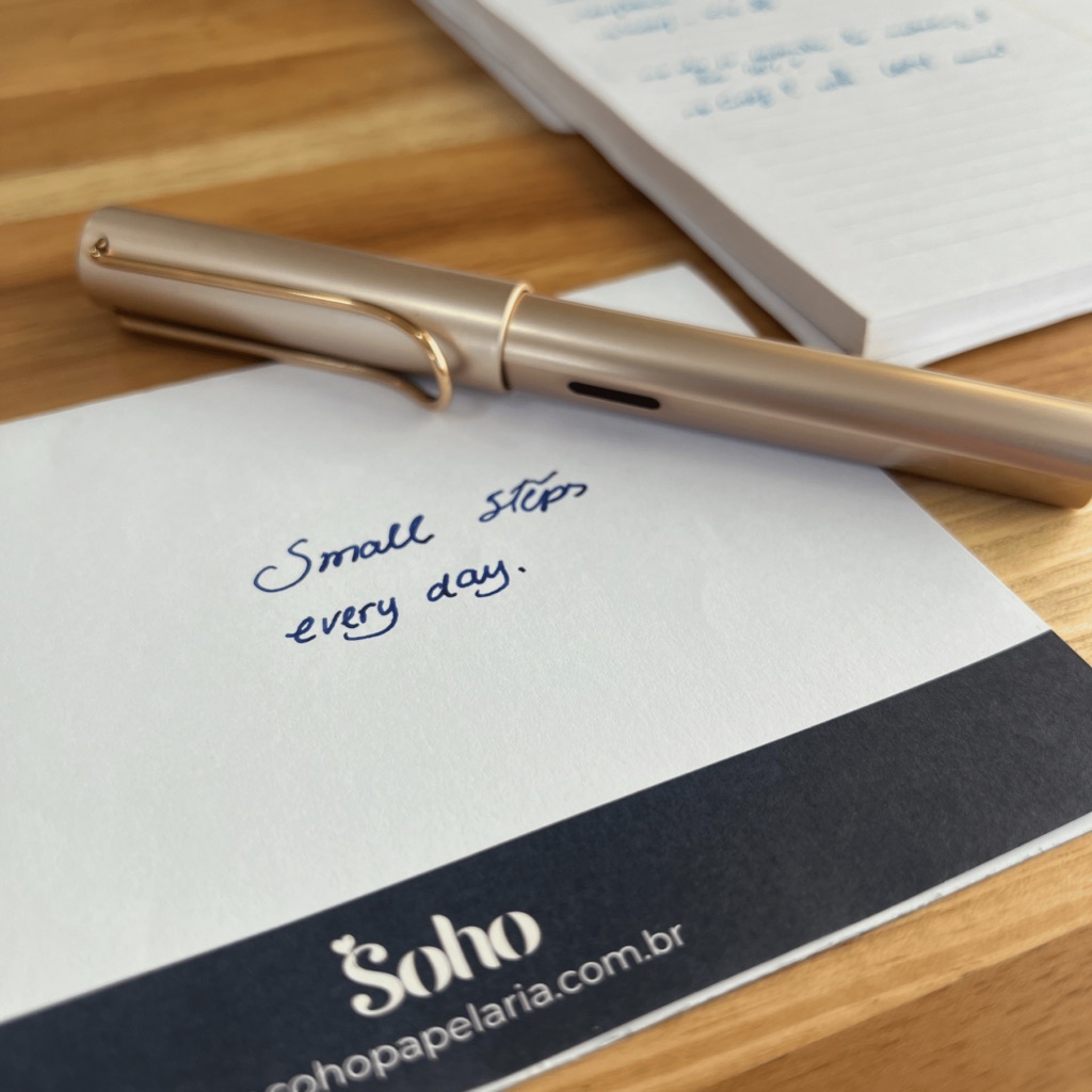 LAMY AL-Star dourada sobre um cartão escrito Small steps every day