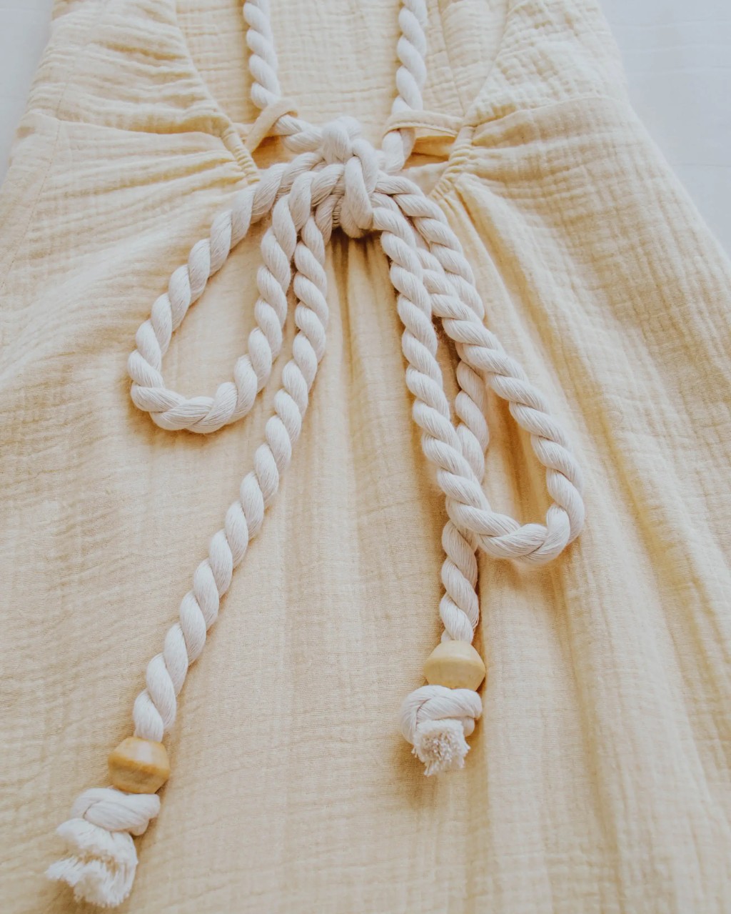 vestido de algod&atilde;o amarelo com textura e al&ccedil;as de cordas com ponteiras de madeira