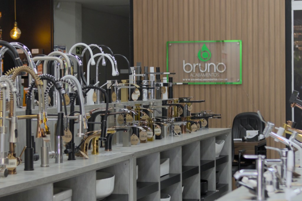 Imagem do showroom da Bruno Acabamentos. Uma foto na horizontal que captura uma parte da loja Bruno Acabamentos. Nessa foto em específico temos diversos tipos de torneiras expostas no mostruário.