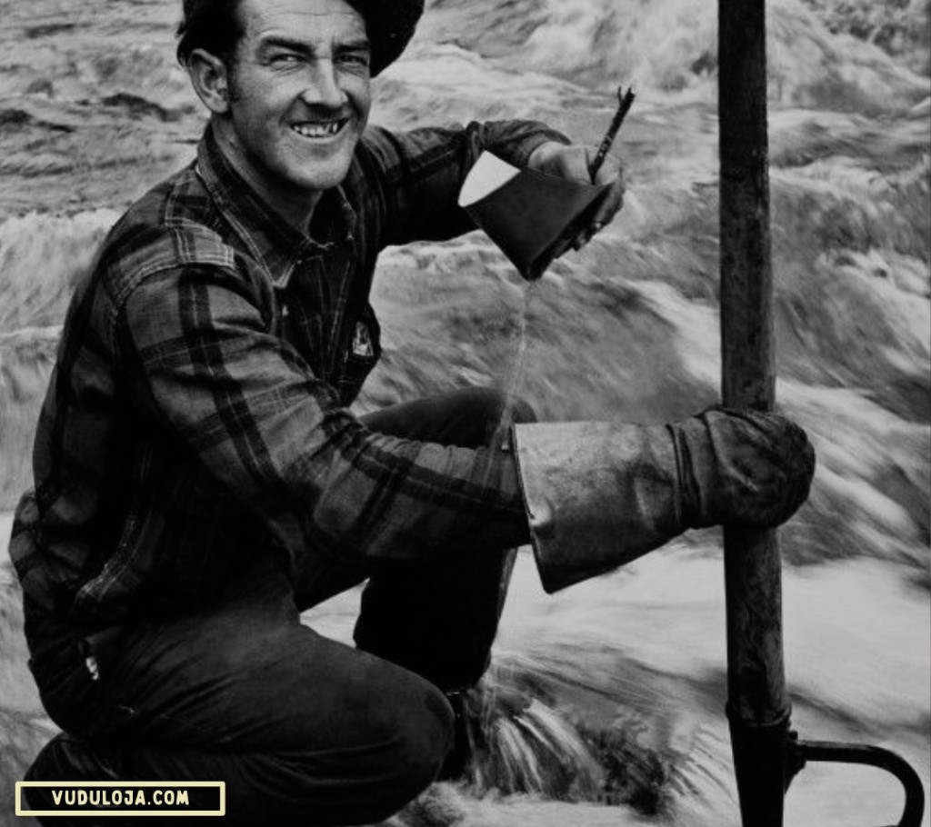 Foto em preto e branco de um homem com luvas e instrumentos de trabalho, vestindo uma camisa work flanelada