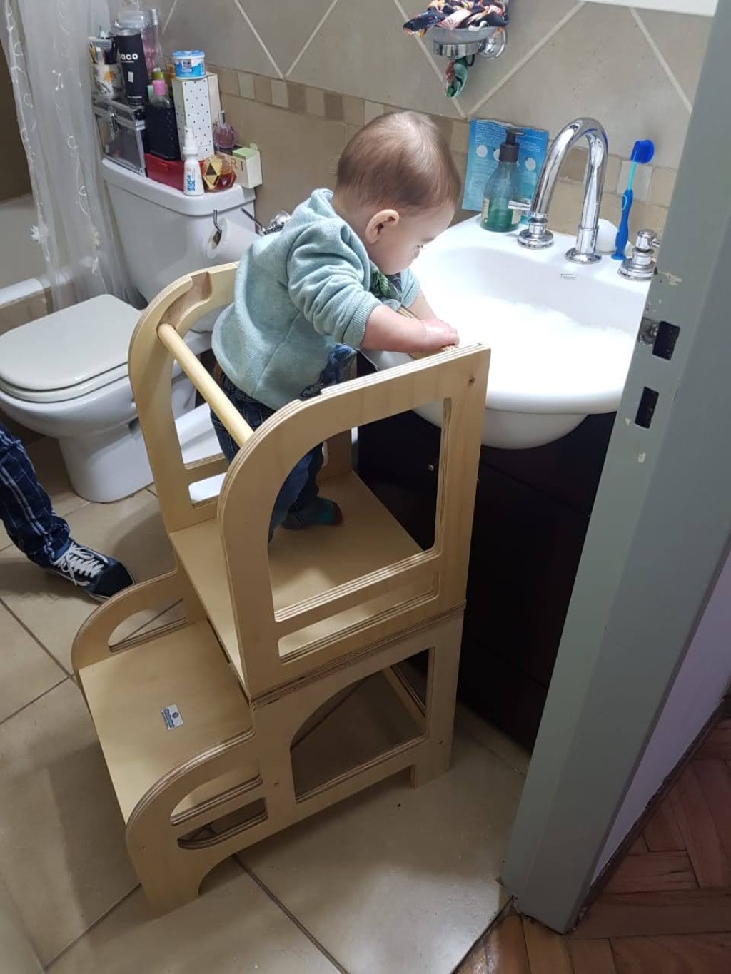 Un bebé lavándose las manos de pie sobre la Torre de Aprendizaje Montedorf