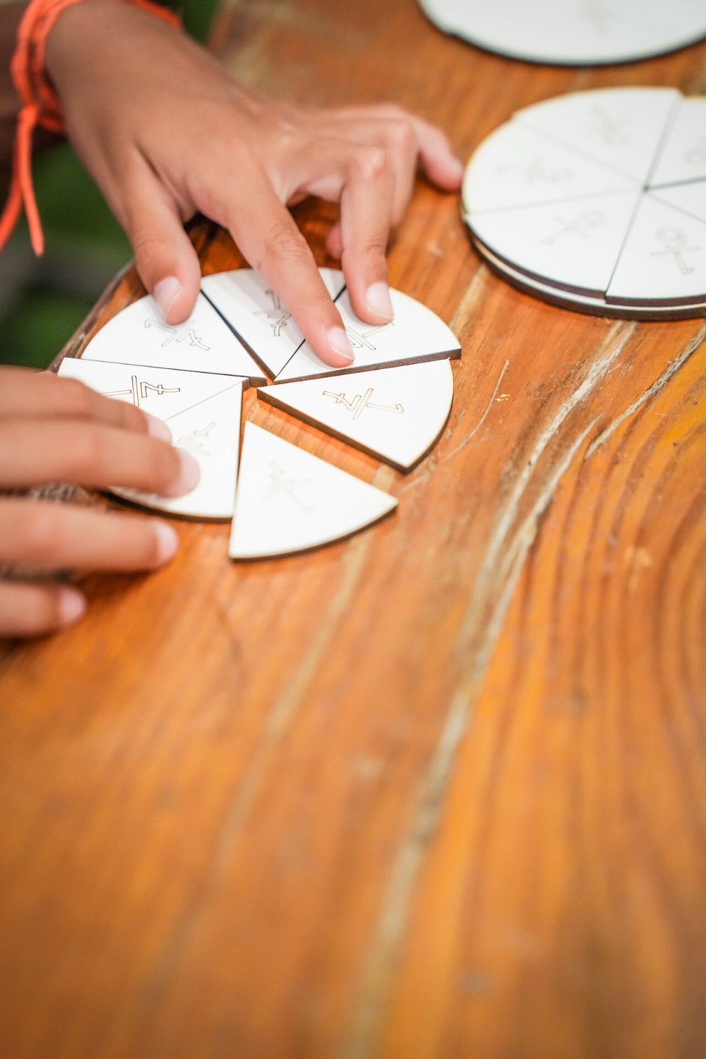 Manos comparando piezas de una caja de fracciones Montessori de madera