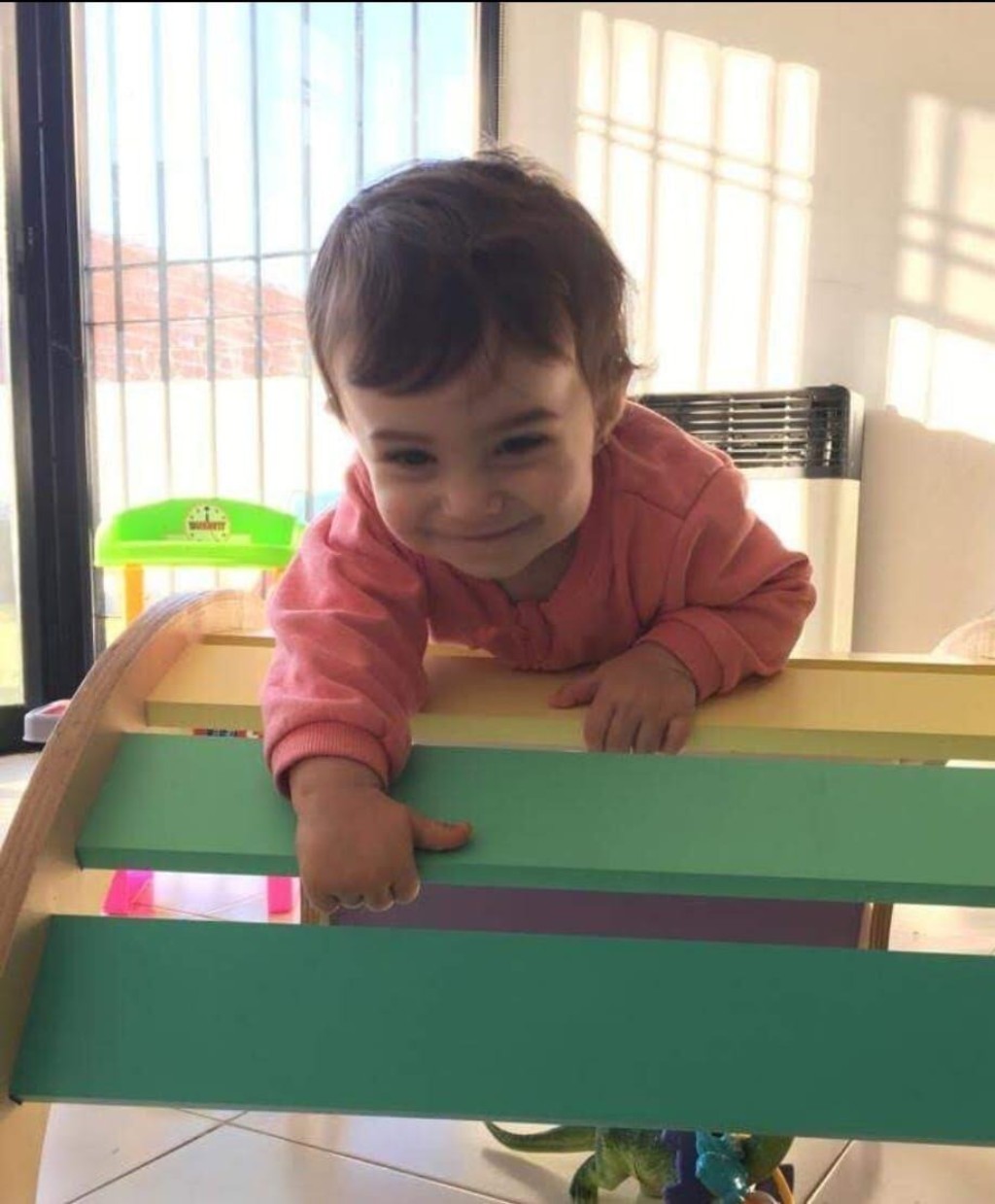  Beb&eacute; gateando en el piso, explorando una pelota cerca de una estructura de movimiento Pikler
