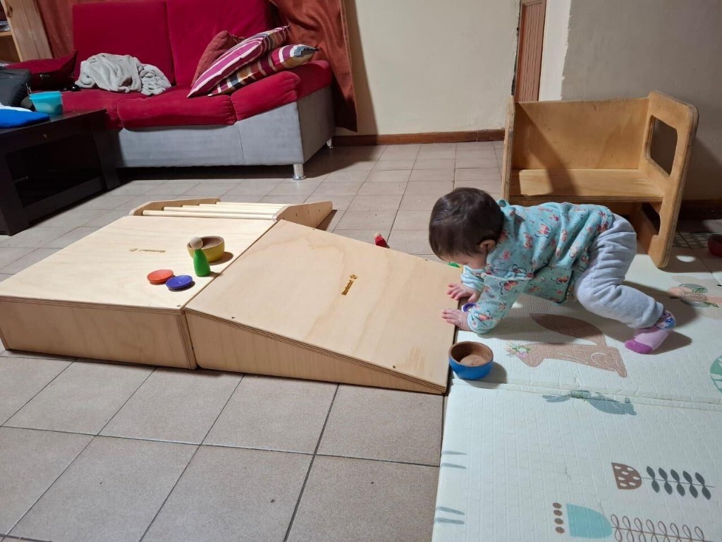 Beb&eacute; gateando hacia la Plataforma de Gateo Pikler de Montedorf, con piezas de encastre de madera arriba