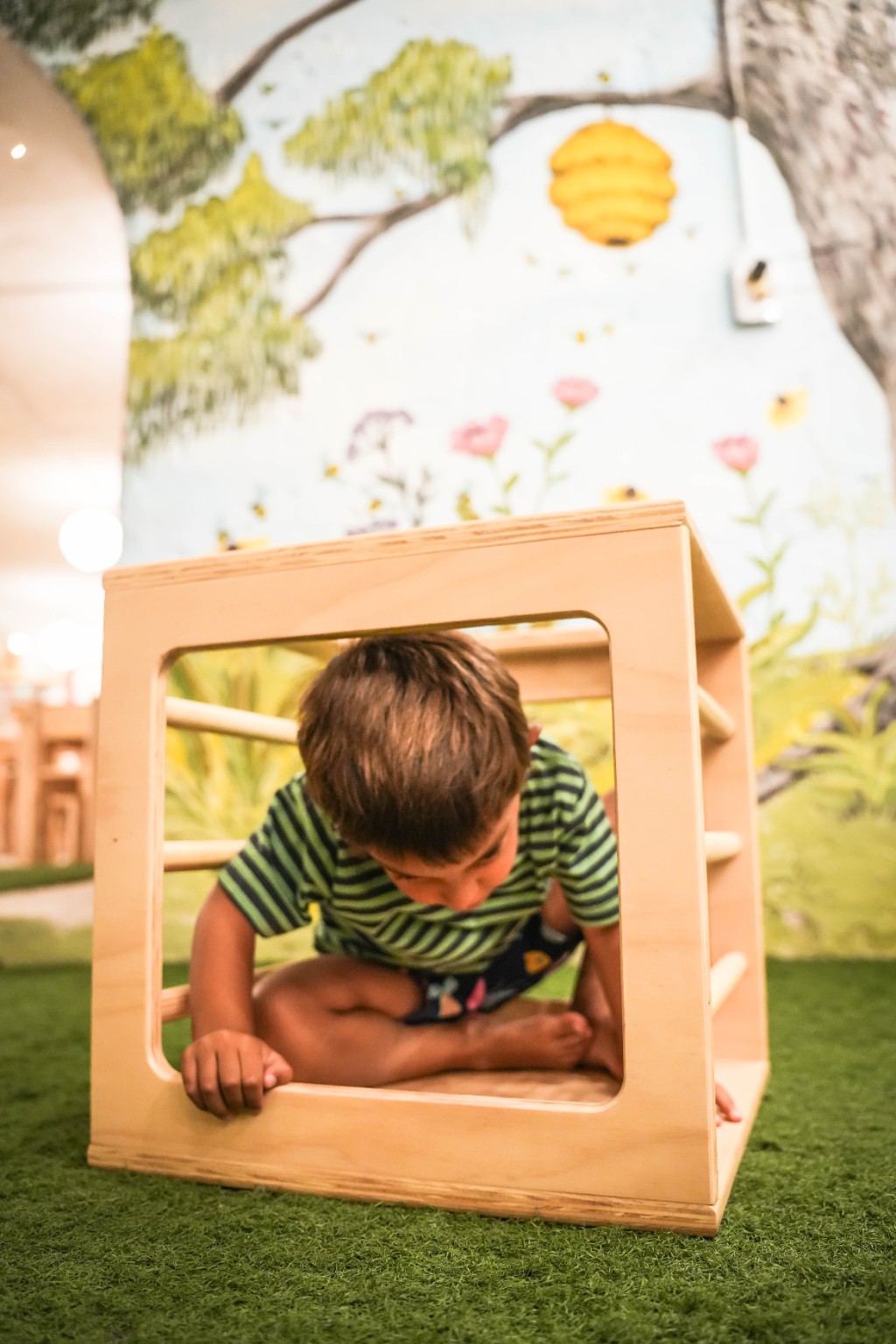 Niño sentado dentro del Cubo Pikler, jugando a esconderse en su interior