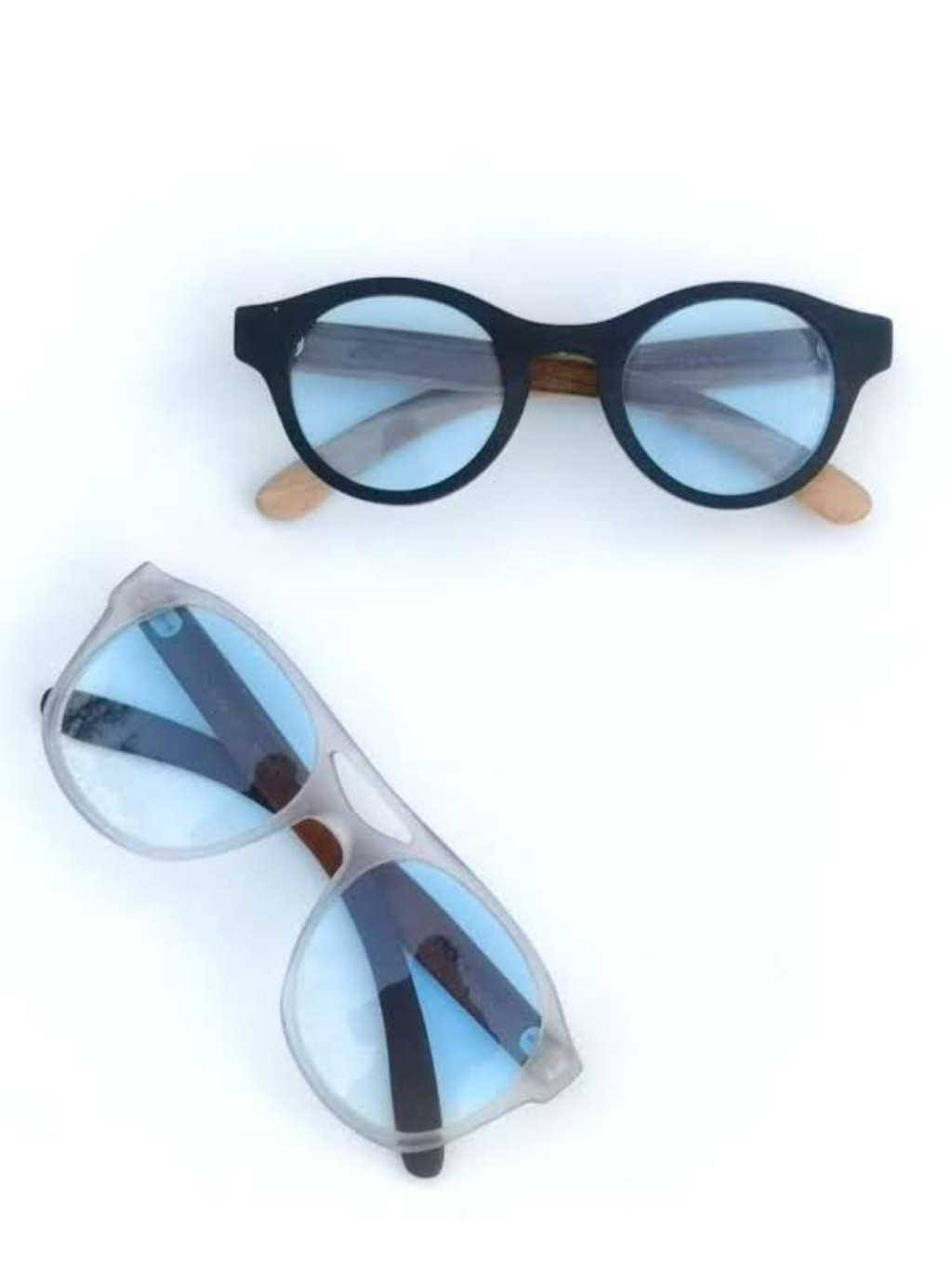 anteojos estilo aviador color cristal y madera con lentes color celeste degrade y anteojos santorini color negro y madera estilo redondo con lentes celeste en degrade ambos sobre fonod blanco