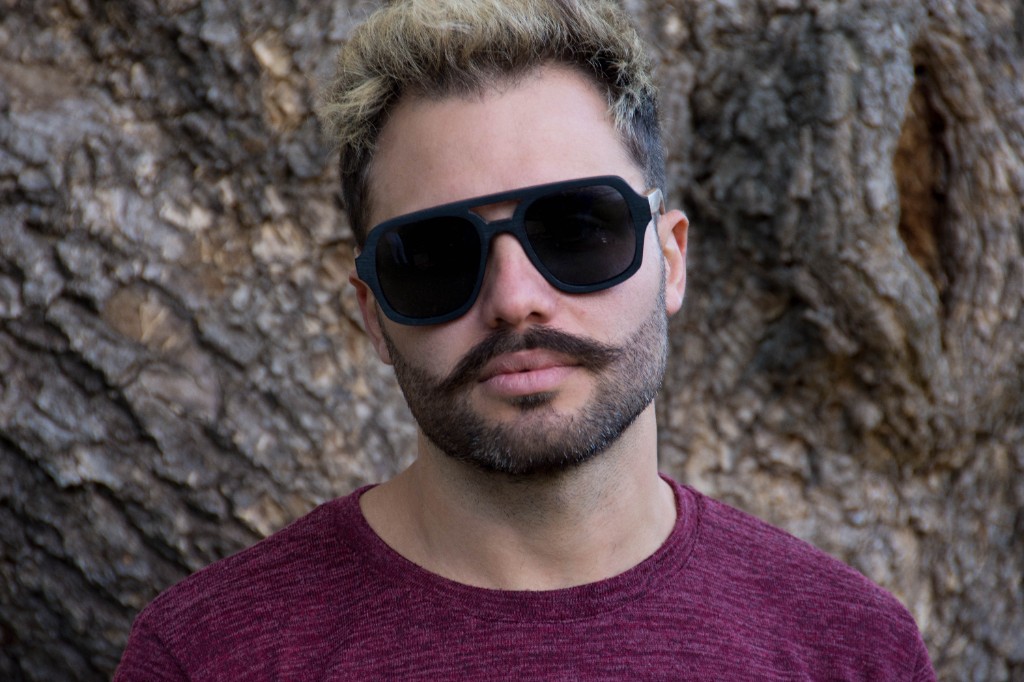 hombre de pelo oscuro y piel blanca con anteojos de sol negros estilo aviador cuadrado marca nomade