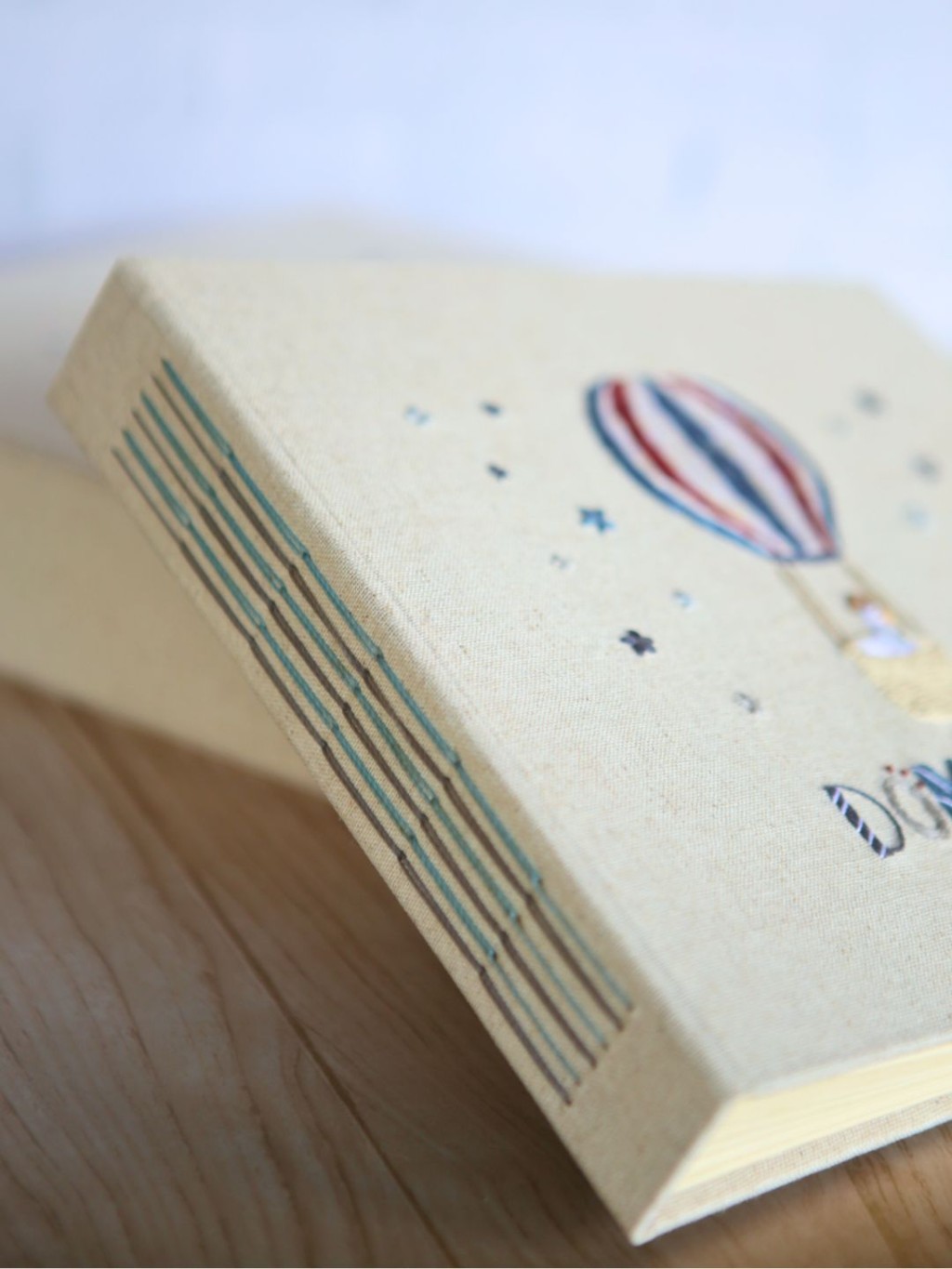 Detalhes da capa de linho bordada à mão do livro do bebê personalizado: costura artesanal na lombada