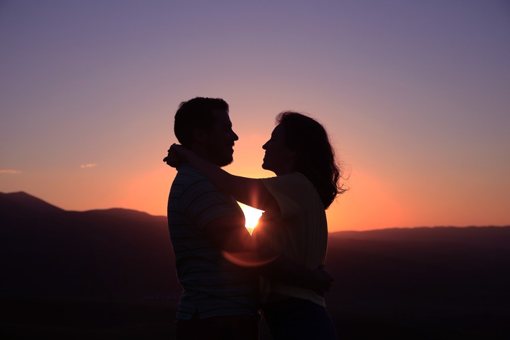 Silueta de una pareja abrazada frente a un atardecer en las monta&ntilde;as, representando la importancia del afecto y la plenitud de vida a pesar de la EPOC.