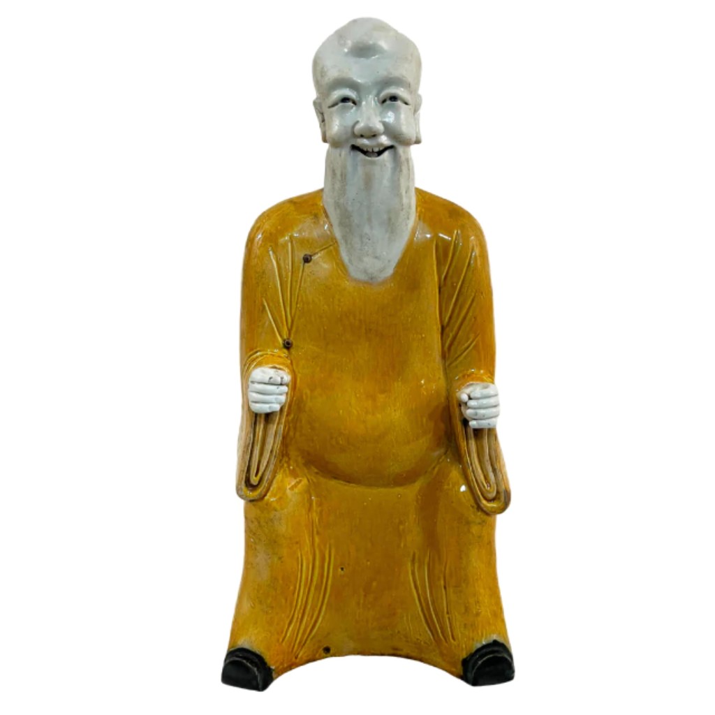 Rara figura em cer&acirc;mica chinesa nas cores amarelo e branco, representando um s&aacute;bio, um s&iacute;mbolo de conhecimento e espiritualidade na cultura tradicional. Datada do final do s&eacute;culo XVI, pertence ao per&iacute;odo do Imperador Wanli (1572-1620), durante a Dinastia Ming (1368-1644), uma era marcada pela excel&ecirc;ncia na produ&ccedil;&atilde;o cer&acirc;mica. Pe&ccedil;as como esta refletem a riqueza art&iacute;stica e a sofistica&ccedil;&atilde;o t&eacute;cnica do per&iacute;odo, sendo altamente valorizadas por estudiosos da arte chinesa.