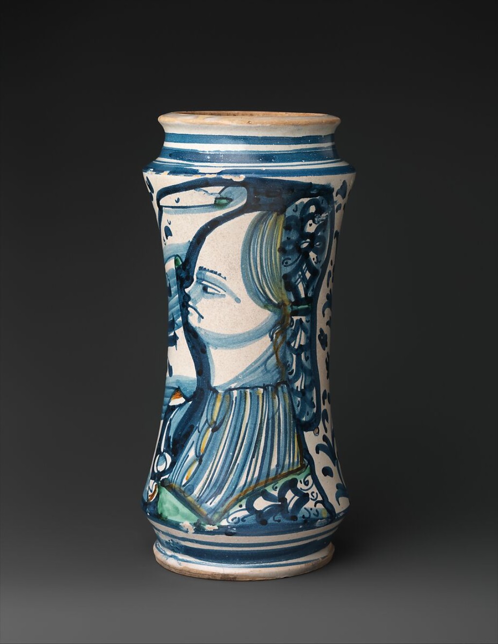 Pote de botica em maiolica italiana com decora&ccedil;&atilde;o figurativa e elementos vegetais, demonstrando o alto n&iacute;vel t&eacute;cnico alcan&ccedil;ado pelas oficinas cer&acirc;micas do Renascimento. Mesmo sendo um objeto utilit&aacute;rio, sua ornamenta&ccedil;&atilde;o revela a valoriza&ccedil;&atilde;o est&eacute;tica dos espa&ccedil;os farmac&ecirc;uticos e a proximidade entre arte e ci&ecirc;ncia.