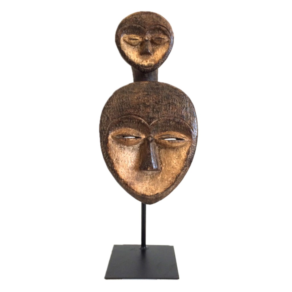 M&aacute;scara africana tradicional em madeira esculpida &agrave; m&atilde;o, marcada por formas geom&eacute;tricas e forte expressividade simb&oacute;lica, caracter&iacute;sticas presentes em diversas tradi&ccedil;&otilde;es art&iacute;sticas da &Aacute;frica Ocidental e Central. Utilizadas em rituais religiosos, dan&ccedil;as cerimoniais e celebra&ccedil;&otilde;es coletivas, pe&ccedil;as como esta representavam ancestrais, esp&iacute;ritos protetores e for&ccedil;as da natureza, desempenhando papel fundamental na vida espiritual e cultural das comunidades africanas.