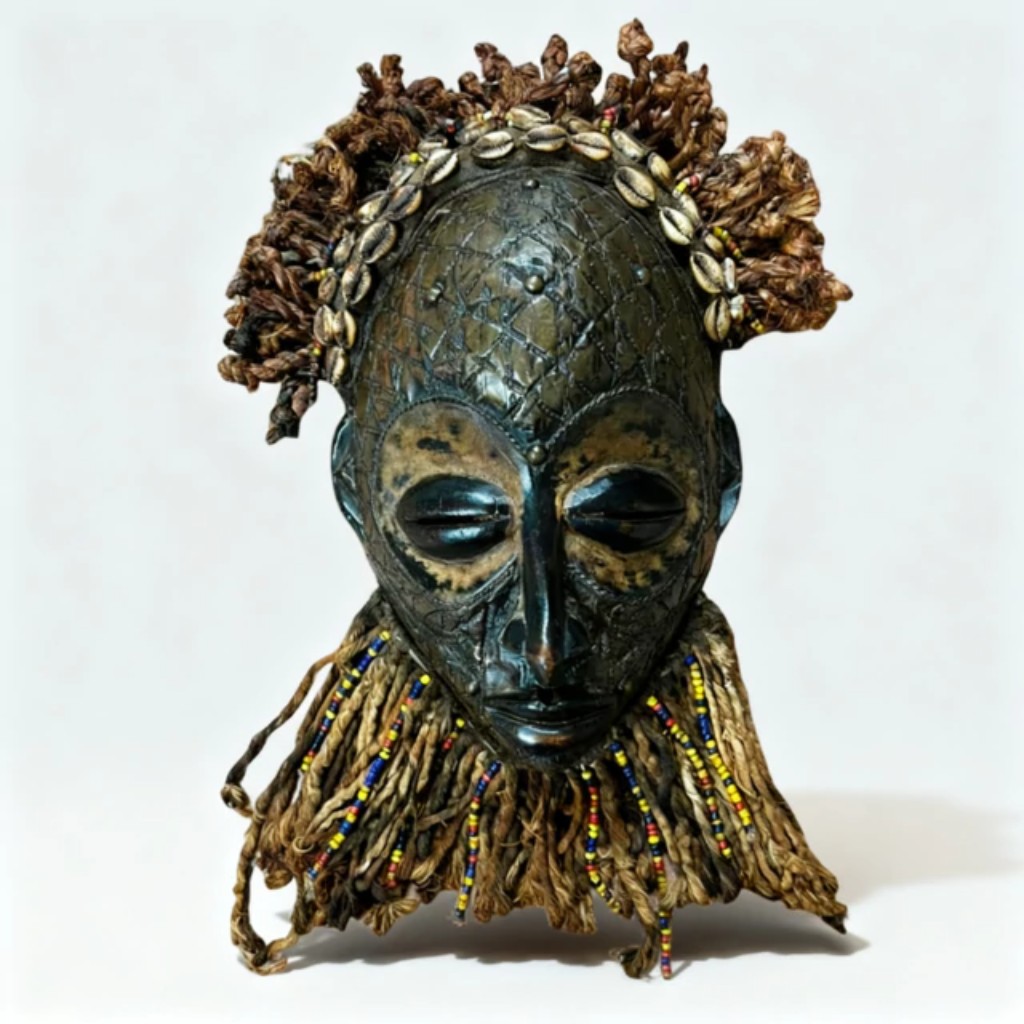 M&aacute;scara africana tradicional em madeira esculpida e policromada, caracterizada pela composi&ccedil;&atilde;o expressiva e pelos padr&otilde;es geom&eacute;tricos que remetem &agrave;s tradi&ccedil;&otilde;es cerimoniais de povos da &Aacute;frica Ocidental. Utilizadas em dan&ccedil;as rituais, festividades e cultos espirituais, m&aacute;scaras como esta exerciam fun&ccedil;&otilde;es sociais e religiosas fundamentais, simbolizando prote&ccedil;&atilde;o, ancestralidade e conex&atilde;o entre o mundo humano e o espiritual.