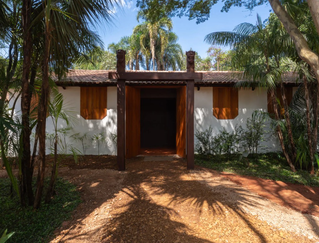 entrada de uma das galerias do Instituto Inhotim cercada pela vegeta&ccedil;&atilde;o tropical caracter&iacute;stica do museu, evidenciando a integra&ccedil;&atilde;o entre arquitetura contempor&acirc;nea, paisagismo e natureza que define a experi&ecirc;ncia imersiva de Inhotim. 