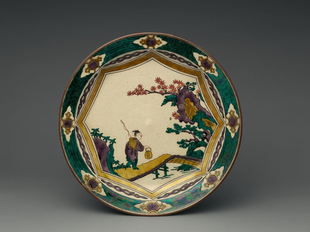 Prato em porcelana Kutani, Jap&atilde;o, per&iacute;odo Edo, s&eacute;culo XVIII, decorado em esmalta&ccedil;&atilde;o policromada e doura&ccedil;&atilde;o, apresentando figura oriental em paisagem naturalista com montanhas, vegeta&ccedil;&atilde;o e arquitetura estilizada. A composi&ccedil;&atilde;o evidencia a tradicional paleta Kutani, marcada pelos tons intensos de verde, p&uacute;rpura, amarelo e azul, caracter&iacute;stica das produ&ccedil;&otilde;es cl&aacute;ssicas da manufatura japonesa.