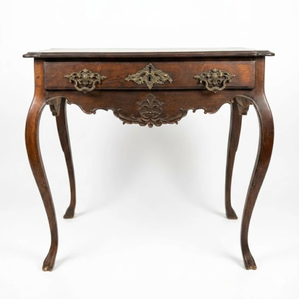 Mesa de encostar executada em jacarandá-da-Bahia maciço, no estilo e época D. José I (1750 a 1777), com tampo retangular moldurado de cantos arredondados, uma gaveta frontal com espelhada e puxadores em bronze cinzelado com motivos rococó, e saia entalhada com recortes ondulados e enrolamentos. Apoia-se sobre quatro pernas cabriolé de delicada curvatura. Obra brasileira do século XVIII