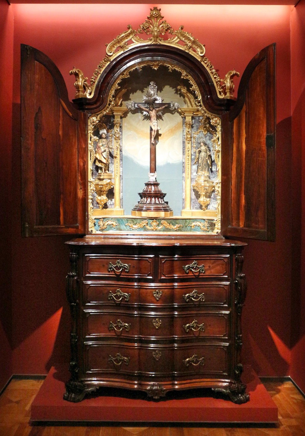 Cômoda barroca brasileira do século XVIII, produzida em jacarandá e ricamente ornamentada com entalhes, ferragens e elementos decorativos inspirados no barroco português. Móveis como este refletem o período de prosperidade da mineração e da consolidação do mobiliário luso-brasileiro, quando a habilidade dos marceneiros locais e a utilização de madeiras nobres deram origem a algumas das peças mais importantes da história das artes decorativas no Brasil