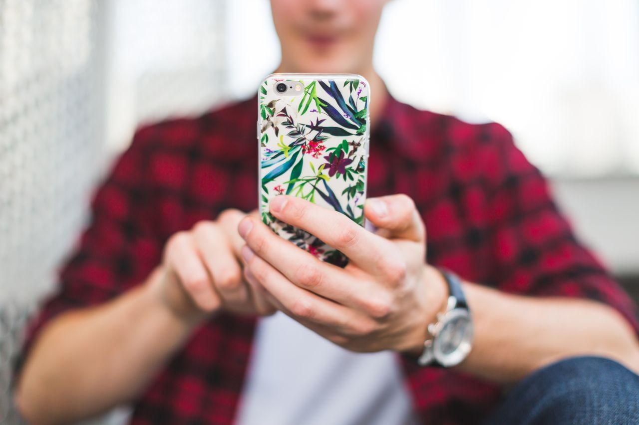 Persona sosteniendo un iPhone con funda de cuero, destacando la protección del dispositivo