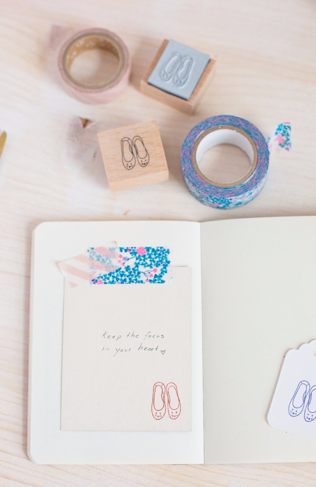 Uso de washi tape en journaling: Plano detalle de un cuaderno abierto decorado con cintas washi tape de patrones bot&aacute;nicos y geom&eacute;tricos, marcando una p&aacute;gina con una nota manuscrita.  