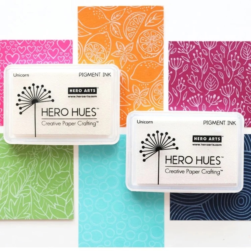 Almohadilla de tinta blanca Hero y papeles de color con sellos aplicados con tinta blanca