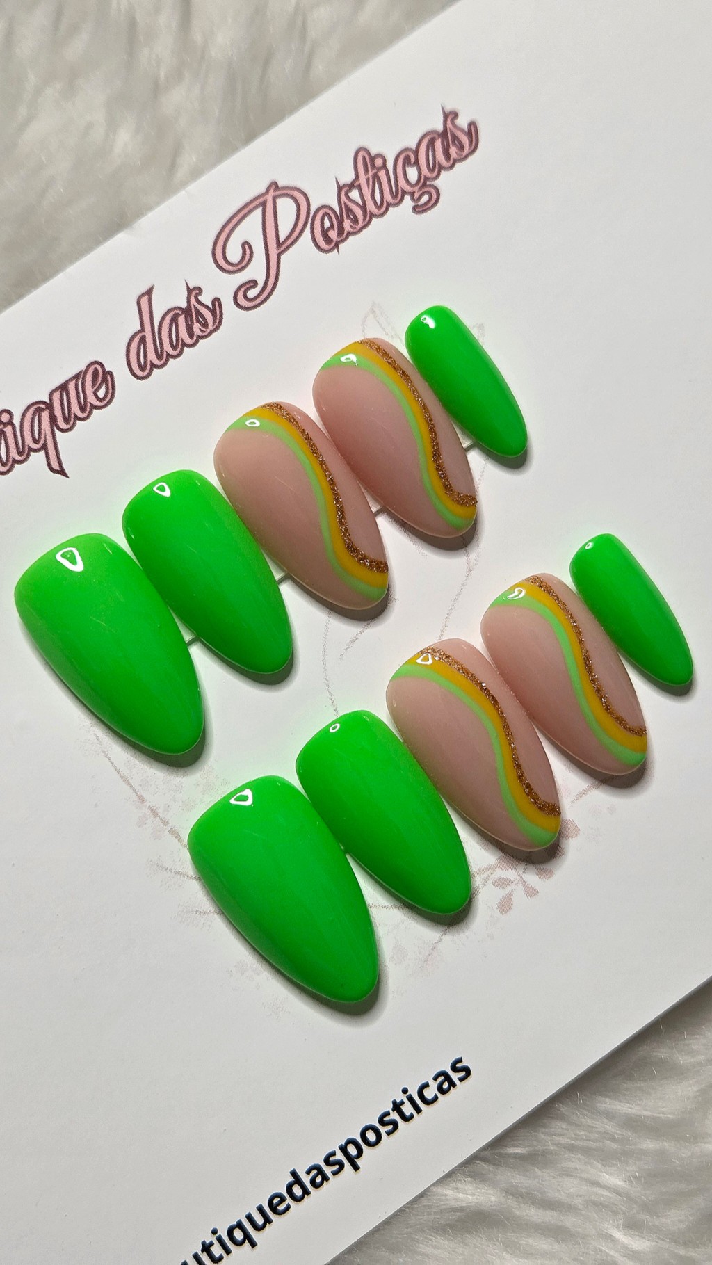 Unhas posti&ccedil;as decoradas verde neon com detalhes ondulados em amarelo, verde claro e glitter dourado sobre base nude elegante.