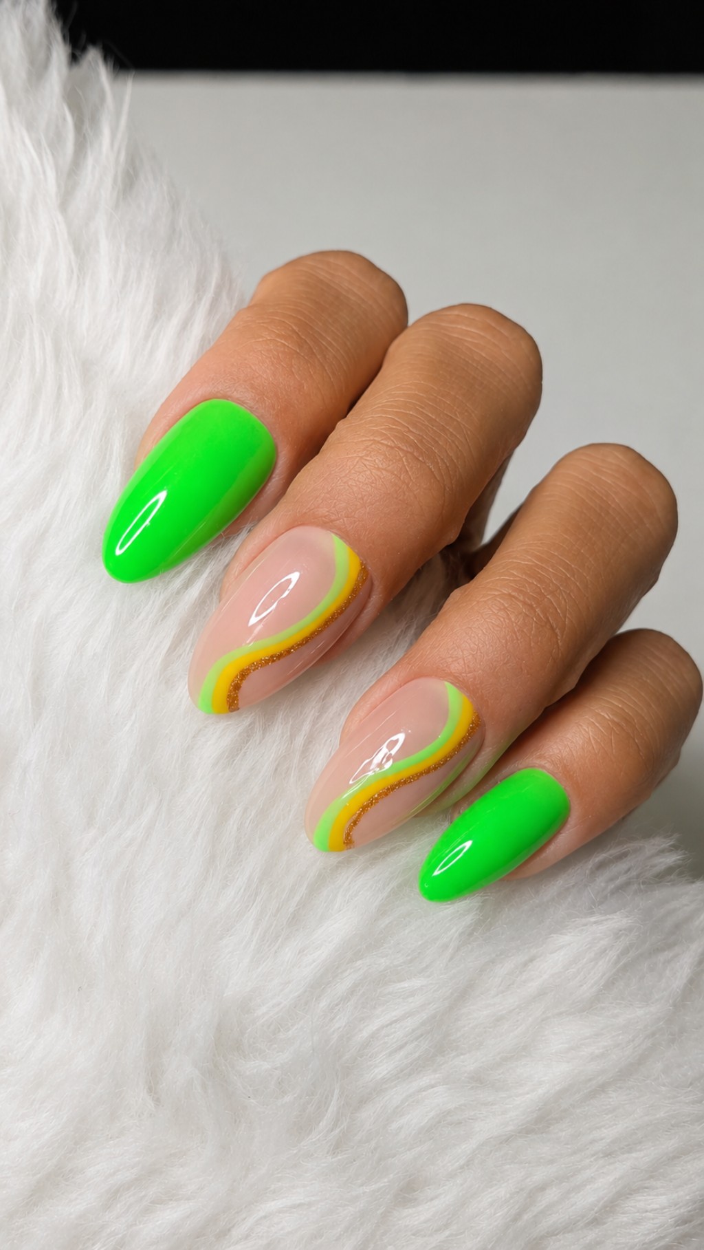 Close de unhas posti&ccedil;as verde neon com nail art ondulada em tons de amarelo e verde, acabamento brilhante e estilo moderno para a Copa do Mundo.