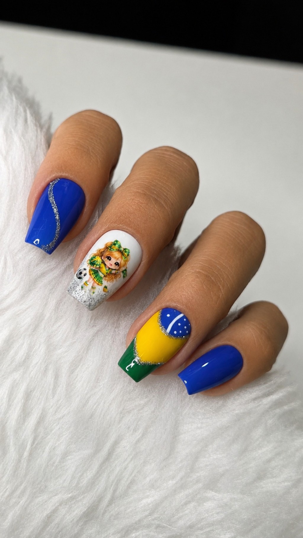 Unhas posti&ccedil;as decoradas em close com esmalta&ccedil;&atilde;o azul intensa, nail art inspirada no Brasil e acabamento brilhante com glitter prateado.