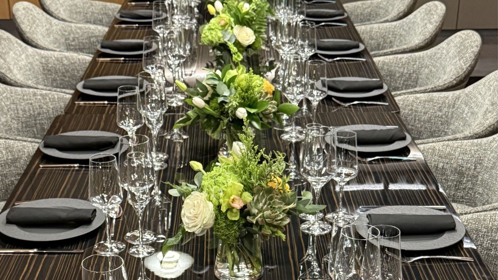 Detalle de una mesa vestida con vajilla, cristalería, servilletas de tela y flores de estación.