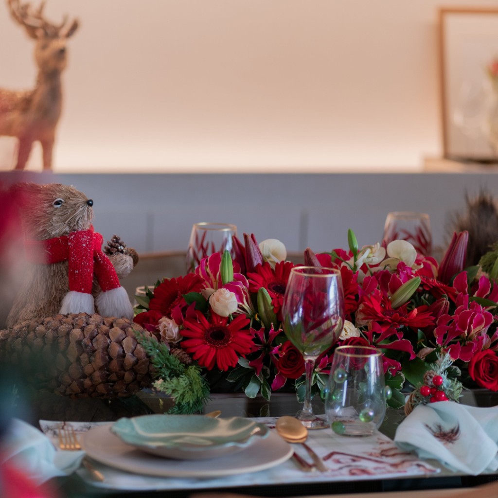 Mesa de Navidad ambientada con flores blancas y bordó, verdes naturales, velas y detalles cálidos