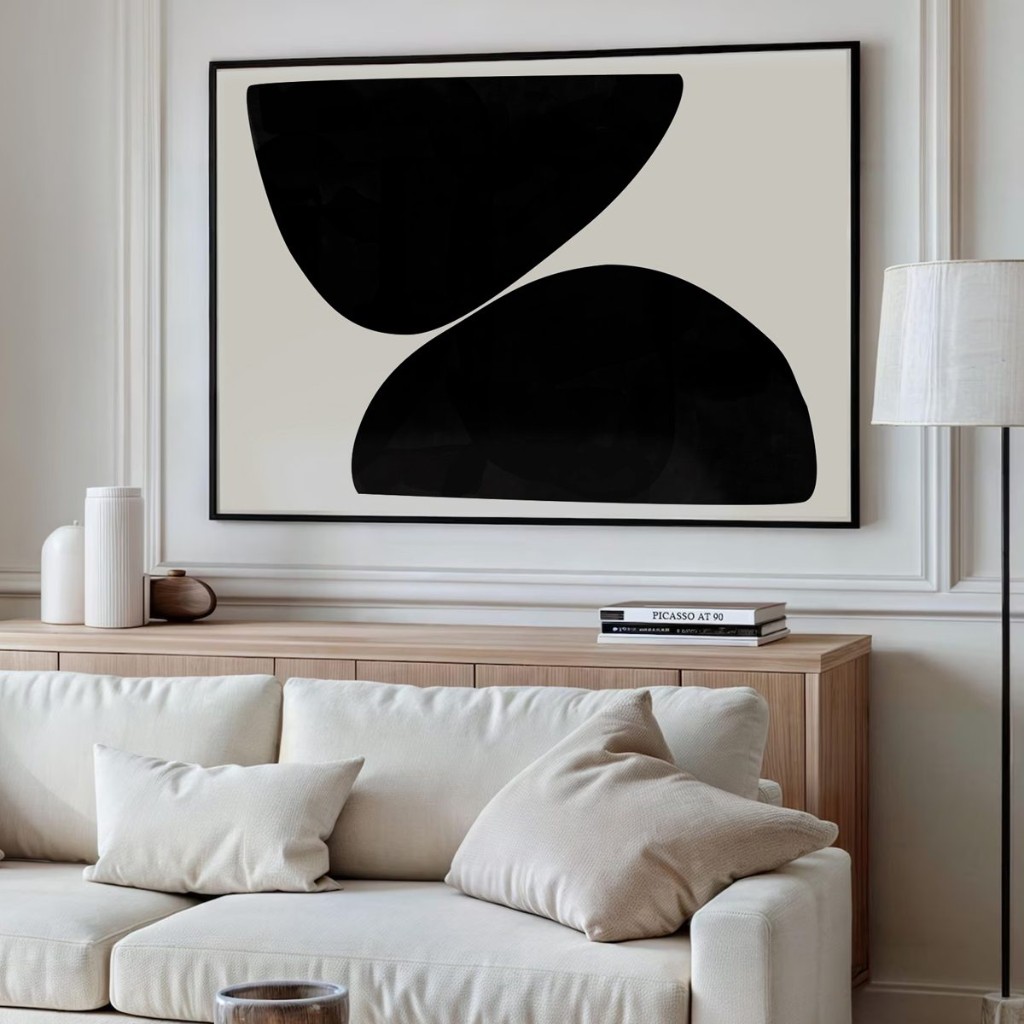 Cuadro grande blanco y negro arriba de un aparador, detr&aacute;s del sill&oacute;n
