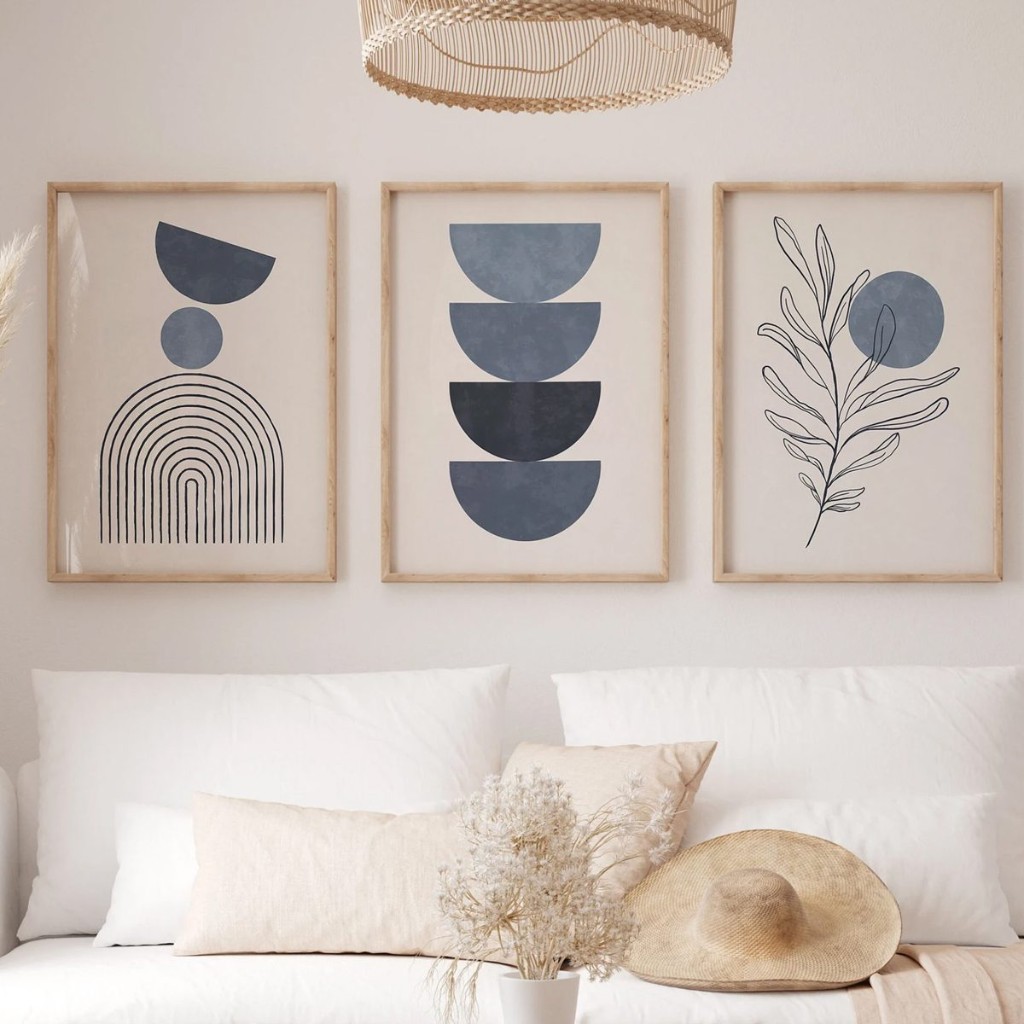 Tr&iacute;o de cuadros abstractos en tonos azules y beige alineados arriba de un sill&oacute;n