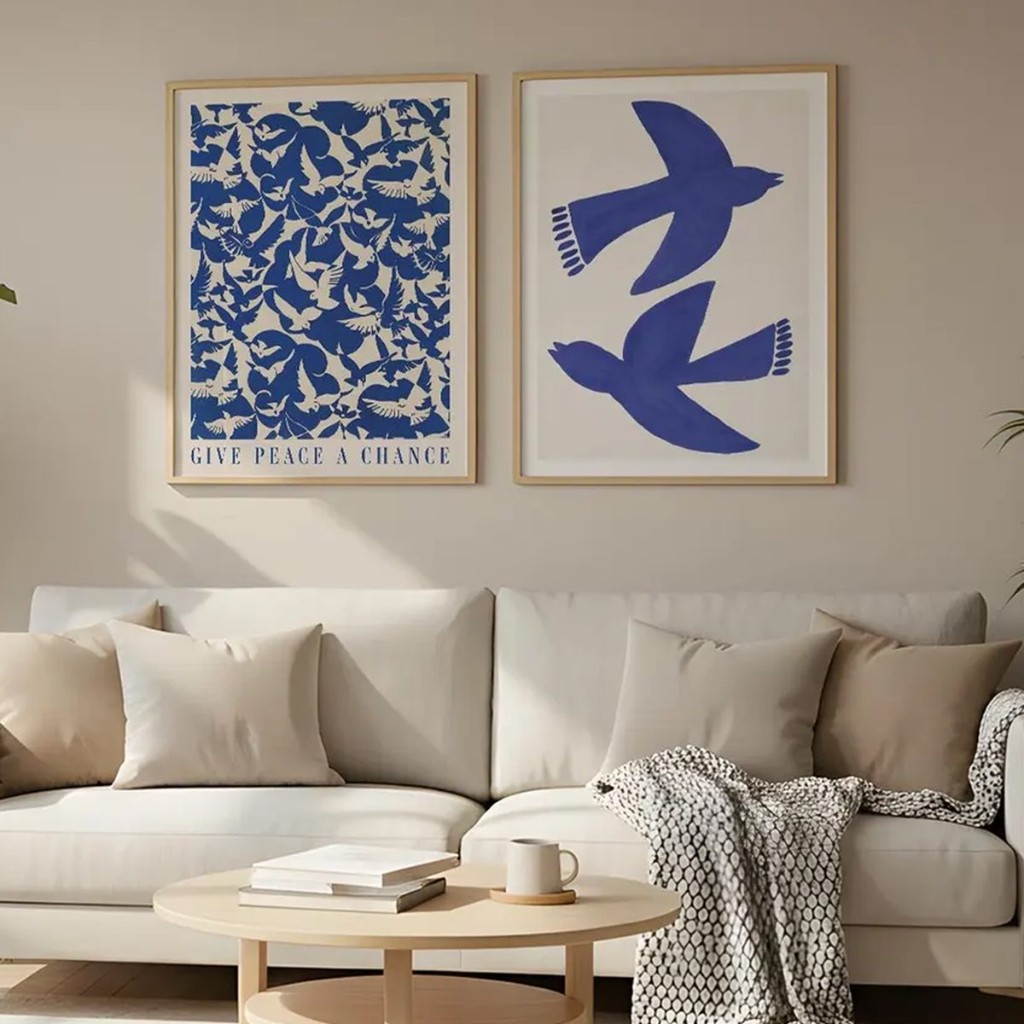 D&uacute;o de cuadros azules con p&aacute;jaros colgado arriba de un sill&oacute;n