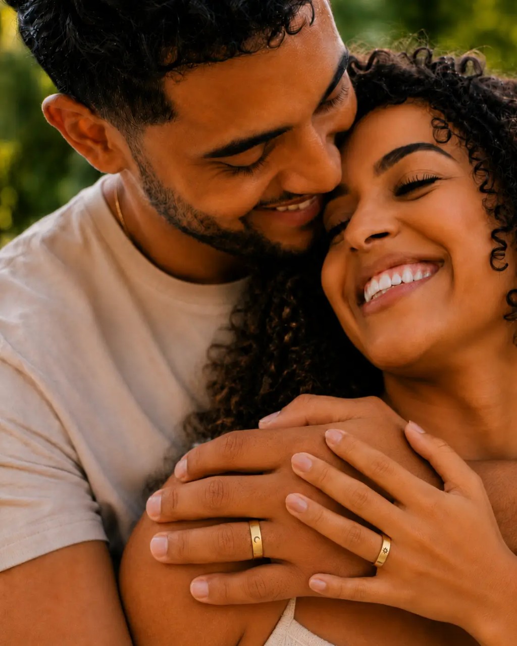 Casal sorrindo em momento rom&acirc;ntico, usando o par de alian&ccedil;as Sol e Lua douradas com s&iacute;mbolos de sol e lua, representando amor, amizade e compromisso.