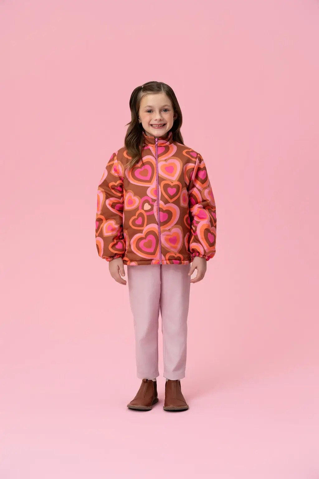 Menina usando jaqueta puffer infantil estampada com cal&ccedil;a clara e bota, em look quentinho e estiloso para dias frios nas f&eacute;rias escolares.