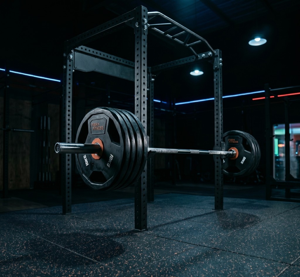 Rack profesional con barra ol&iacute;mpica y discos en gimnasio comercial