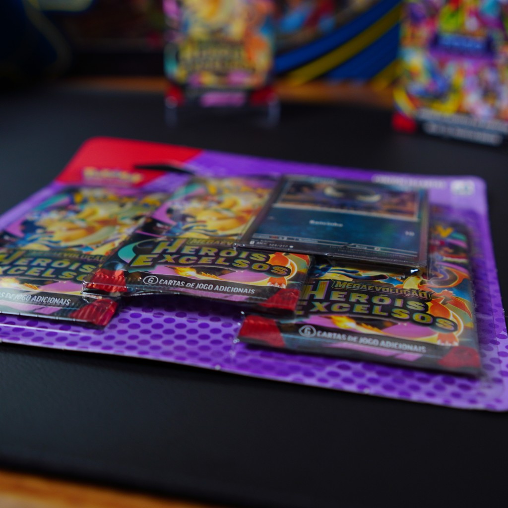 Blister triplo de pok&eacute;mon TCG com booster e combo de booster ao fundo