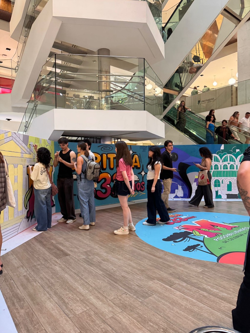 Pessoas pintando mural de arte, junto com Prosa Graffiti, no Shopping Mueller. Curitiba