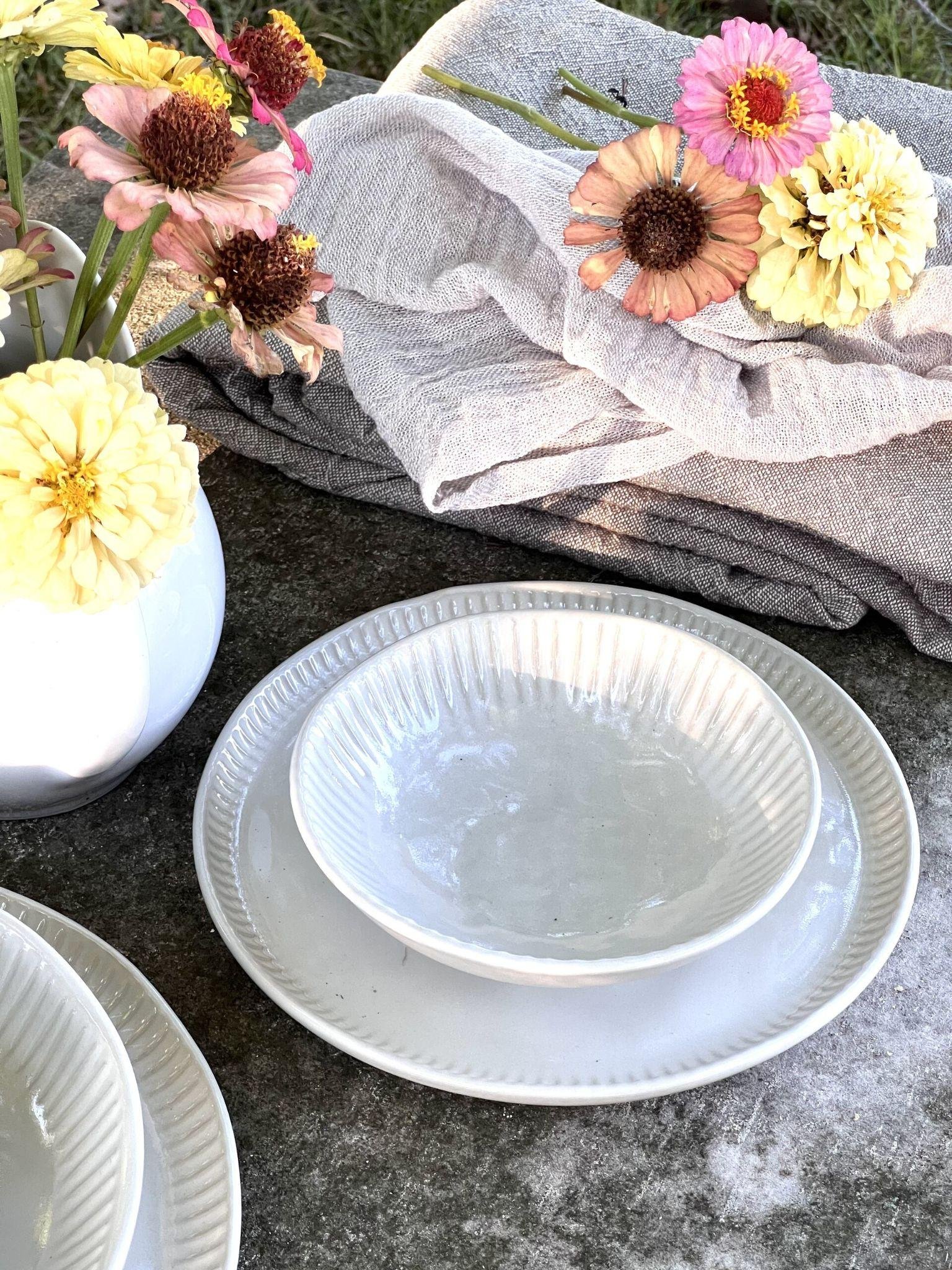 Florero de cer&aacute;mica con flores frescas sobre una mesa