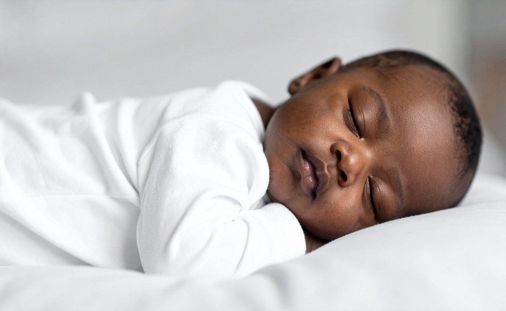 Crian&ccedil;a pequena sorrindo dentro da banheira, brincando com um brinquedo de banho em tons delicados, em um banheiro clean e minimalista.