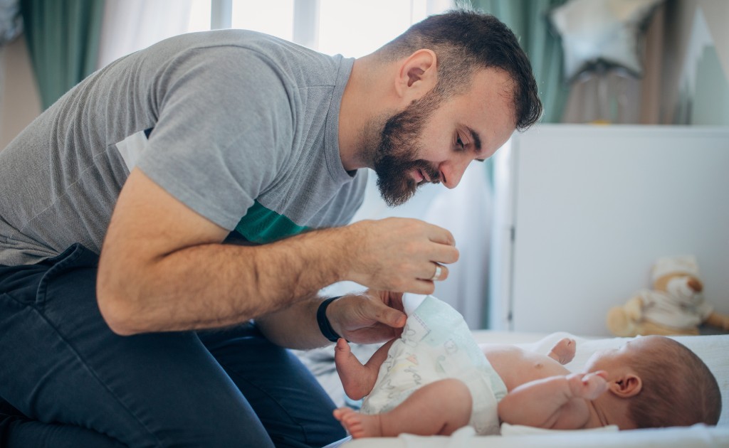 Pai trocando fralda do bebê em momento de cuidado diário