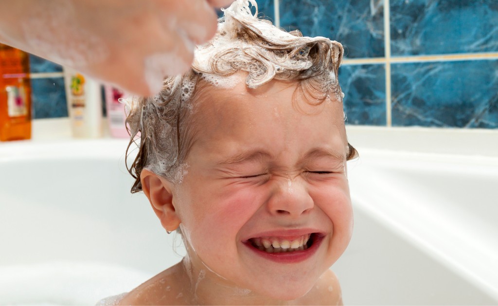 Criança lavando o cabelo no banho com espuma suave